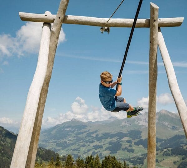 Junge fliegt mit der Tyrolienne durch die Lüfte auf dem Vogellisi Erlebnisweg in Adelboden.
